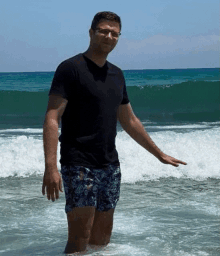 a man in shorts and a black shirt is standing in the ocean
