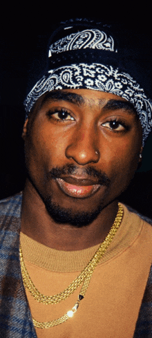 a close up of a man wearing a bandana and gold chain