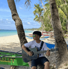 a man sits under a palm tree playing a guitar in front of a green harley boat