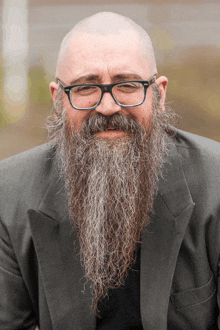 a man with glasses and a long beard is smiling for the camera