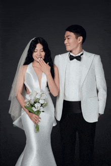 a bride in a white dress and a groom in a tuxedo pose for a picture