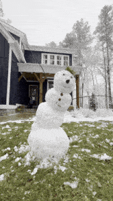 a snowman in front of a blue house with trees in the background