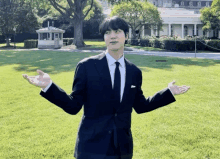 a man in a suit and tie stands in front of the white house