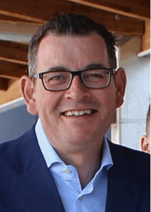 a man wearing glasses and a blue suit smiles for the camera .