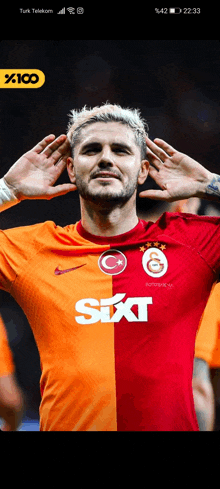 a soccer player wearing a red and orange shirt with sixt written on it