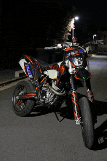 a ktm dirt bike is parked on a street at night