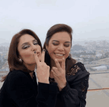 two women are posing for a picture and one is blowing a peace sign