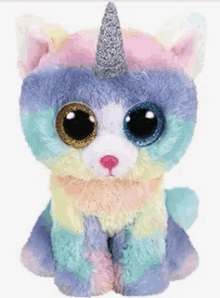 a stuffed animal with big eyes and a unicorn horn is sitting on a white background .