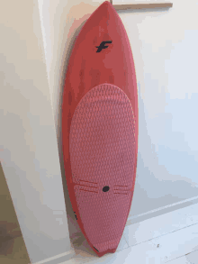 a red surfboard with the letter f on the top