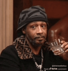 a man with a beard wearing a hat and holding a glass of water .