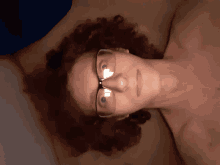 a naked man wearing glasses is laying on his back