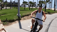 a man is riding a bike on a sidewalk in front of palm trees