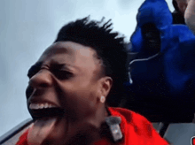 a man in a red shirt sticks his tongue out