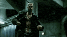 a man in a leather jacket is running in a dark room ..