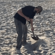a man is using a shovel to dig in the sand