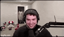 a man wearing headphones is sitting in front of a microphone and smiling .