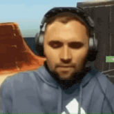 a man wearing headphones and a blue hoodie with an adidas logo