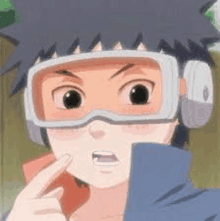 a young boy wearing goggles and headphones is pointing at his face .