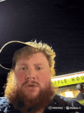 a man with a beard stands in front of a waffle house sign
