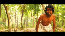 a shirtless man is standing in the middle of a forest