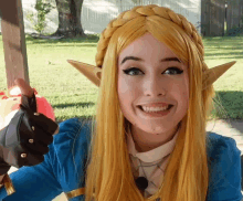 a woman with long blonde hair and elf ears smiles