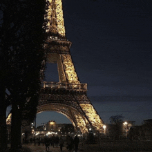 the eiffel tower is lit up at night with people walking around