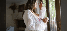 a woman in a white shirt looks out a window