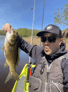 a man holding a fish with a patch on his hat that says ' fishing club ' on it