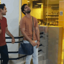 two men standing next to each other in a library with a sign on the wall that says ' no smoking '