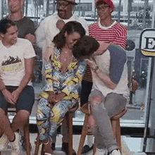 a group of people are sitting on stools and a man is kissing a woman .