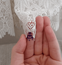 a person is holding a piece of lace with a drawing of a face on it