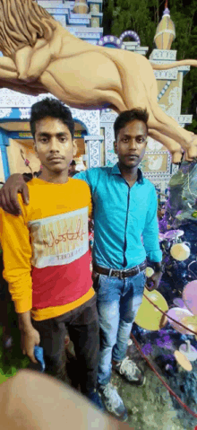 two young men are posing for a picture in front of a statue