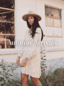 a woman wearing a hat and a dress is standing in front of a building that says autumn arrivals on it