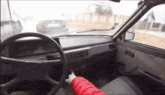 a person in a red jacket is driving a car with a steering wheel
