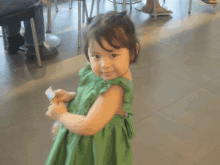 a little girl in a green dress holds a card