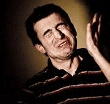 a man in a striped shirt is making a funny face with his hands .