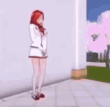 a girl with red hair is standing on a sidewalk in front of a white wall .