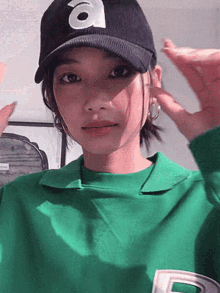 a woman wearing a green shirt and a hat with the letter a on it