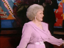 an older woman in a purple dress is dancing on a stage