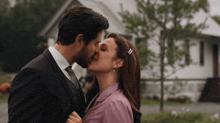 a man and a woman kissing in front of a house
