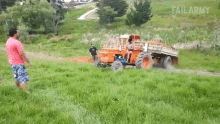 a man in a red shirt watches a tractor pulling a trailer in a field with failarmy written on the bottom right