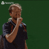 a man is making a shhh gesture in front of a tennis tv logo