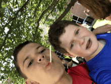 two young boys are posing for a picture with a straw in their mouth