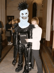 a man in a death note costume stands next to another man