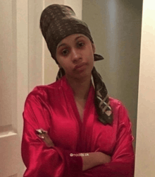 a woman wearing a red robe and a head scarf stands with her arms crossed in front of a mirror ..