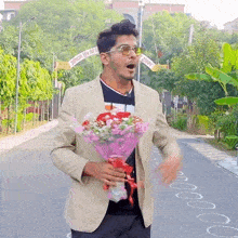 a man in a tan jacket is holding a bouquet of flowers in front of a sign that says ' a '