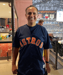 a man wearing a blue astros jersey stands in a stadium