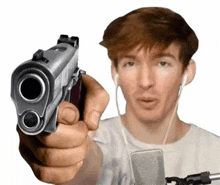 a man is pointing a gun at the camera while wearing ear buds .