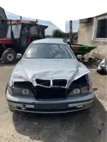 a silver car with a bmw logo on the front is parked in a dirt lot