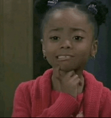 a little girl is making a funny face with her hand on her chin .
